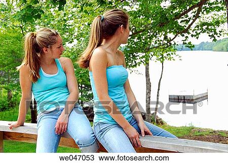 13 and 18 year old sisters sitting on deck railing at cottage looking out onto lake View Large Photo Image Stock Image - 13 and 18 year old sisters sitting on deck railing at cottage looking out onto lake. Fotosearch
