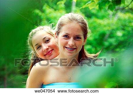 13 and 18 year old sisters sitting together on railing at cottage View Large Photo Image Picture - 13 and 18 year old sisters sitting together on railing at cottage. Fotosearch