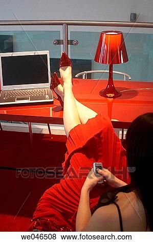 21 year old girl sitting with her feet up on a desk wearing red shoes, skirt on a red table with a laptop, and mobile View Large Photo Image Stock Photo - 21 year old girl sitting with her feet up on a desk wearing red shoes, skirt on a red table with a laptop, and mobile. Fotosearch