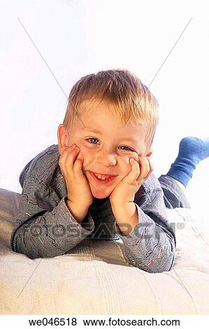 3 year old boy at nursery smiling into camera, lying on his tummy. View Large Photo Image Stock Photo - 3 year old boy at nursery smiling into camera, lying on his tummy.. Fotosearch