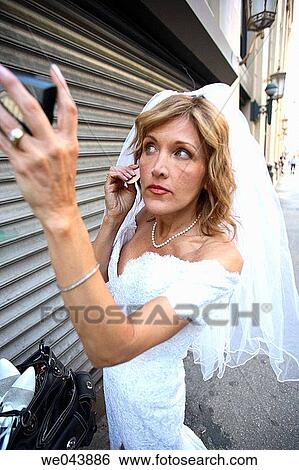 Stock Photograph - Bride on street fixing her makeup. Fotosearch