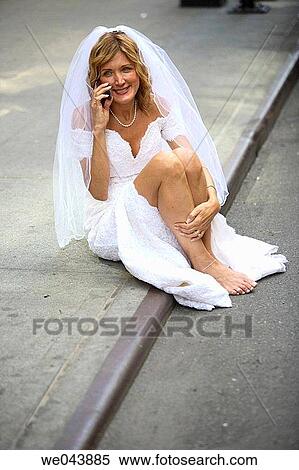 Stock Photography - Bride sitting on curb talking on cell phone. Fotosearch