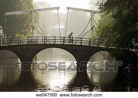 Cycling on a bridge. Amsterdam. Netherlands. View Large Photo Image Stock Image - Cycling on a bridge. Amsterdam. Netherlands.. Fotosearch