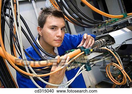 Stock Image - Fatronik Research Centre, San Sebastian Technological Park, Donostia, Gipuzkoa, Basque Country. Technician checking the electric and hydraulic systems of a tool-machine.. Fotosearch