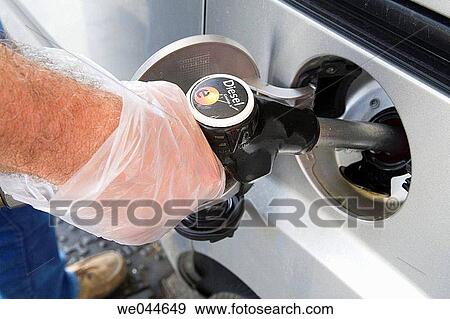 Gloved hand holding gas pump nozzle in car fuel tank View Large Photo Image Stock Photo - Gloved hand holding gas pump nozzle in car fuel tank. Fotosearch