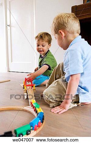Two little boys playing with a wooden train View Large Photo Image Stock Photo - Two little boys playing with a wooden train. Fotosearch