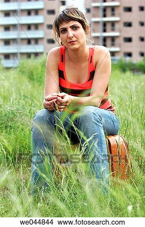 Young woman sitting on suitcase in lot View Large Photo Image Picture - Young woman sitting on suitcase in lot. Fotosearch