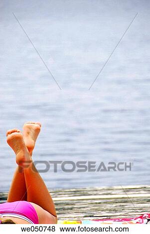 Stock Photo - 18 yr old girl laying on dock. Fotosearch