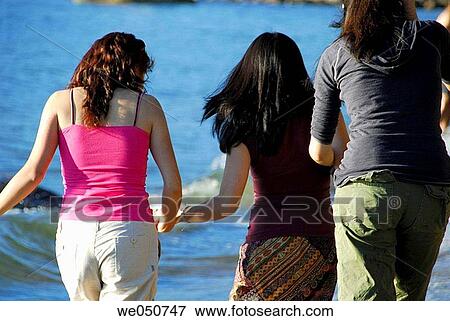 Stock Photo - 3 asian girls walking along the beach together. Fotosearch