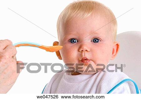 Stock Photograph - Baby fed with a spoon. Fotosearch