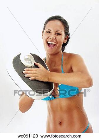 Stock Image - Bathroom scale, clipping path, brunette, 20's. Fotosearch