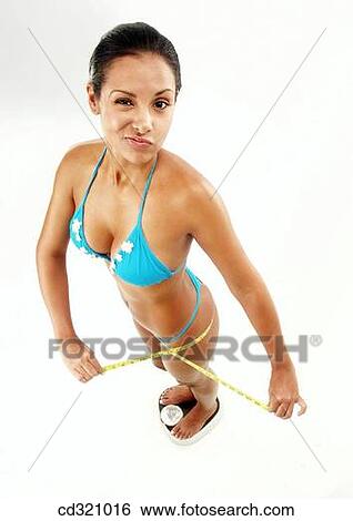 Stock Photograph - Bathroom scale, clipping path, brunette, 20's. Fotosearch