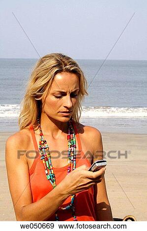 Beautiful blonde woman looking upset at a phone on an beach in India. View Large Photo Image Stock Photo - Beautiful blonde woman looking upset at a phone on an beach in India.. Fotosearch
