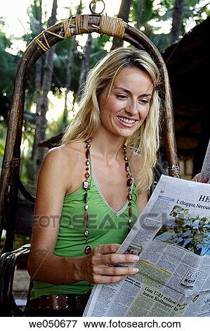 Stock Photo - Beautiful blonde woman sat outside reading the paper, shot in the morning in India.. Fotosearch