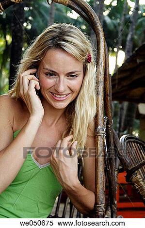 Stock Photography - Beautiful blonde woman sat outside talking on the phone, shot in the morning in India.. Fotosearch