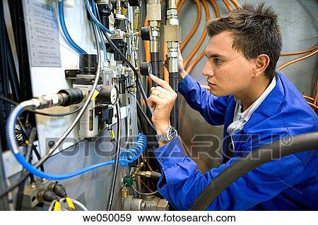 Stock Photo - Fatronik Research Centre, San Sebastian Technological Park, Donostia, Gipuzkoa, Basque Country. Technician checking the electric and hydraulic systems of a tool-machine.. Fotosearch