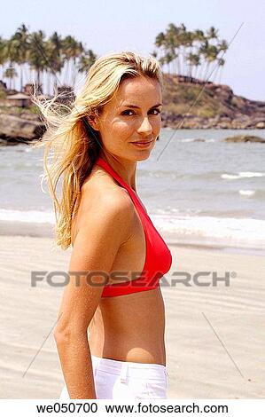 Stock Image - Portrait of beautiful blonde woman in red bikini top on a beach in India.. Fotosearch