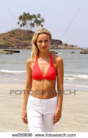 Portrait of beautiful blonde woman in red bikini top and white pants walking on a beach in India. View Large Photo Image Stock Photograph - Portrait of beautiful blonde woman in red bikini top and white pants walking on a beach in India.. Fotosearch