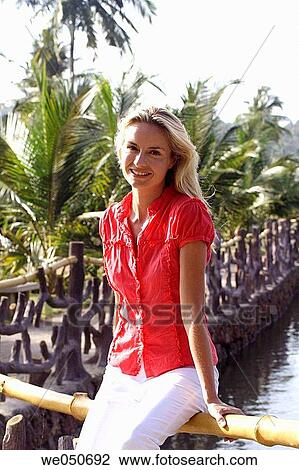 Portrait of beautiful blonde woman sat on a fence by a lagoon in India View Large Photo Image Stock Image - Portrait of beautiful blonde woman sat on a fence by a lagoon in India. Fotosearch