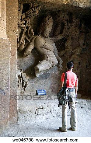 Tourist looking at stone carvings in rock-cut temple on Elephanta Island. Mumbai (ex Bombay). India View Large Photo Image Stock Photo - Tourist looking at stone carvings in rock-cut temple on Elephanta Island. Mumbai (ex Bombay). India. Fotosearch