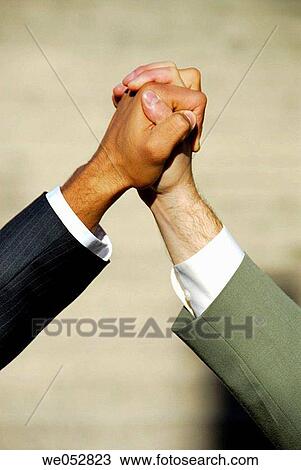 2 young male business men clasping hands together View Large Photo Image Stock Image - 2 young male business men clasping hands together. Fotosearch