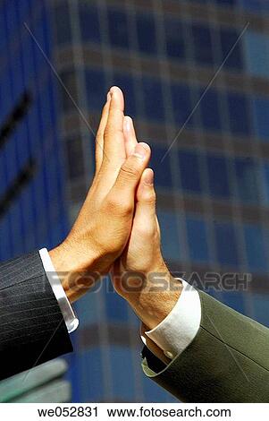 2 young male business men putting hands together with building in background View Large Photo Image Stock Image - 2 young male business men putting hands together with building in background. Fotosearch