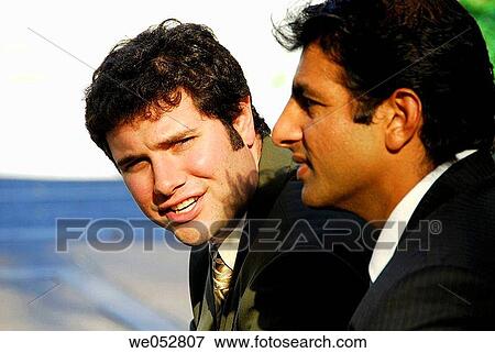 Stock Photo - 2 young male business men sitting together having discussion outdoors. Fotosearch