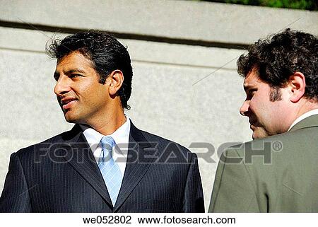 2 young male business men standing together looking sideways View Large Photo Image Stock Image - 2 young male business men standing together looking sideways. Fotosearch