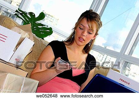 Stock Photo - 20 Yr old woman home shopping on laptop computer using credit card. Fotosearch