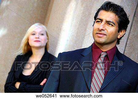 35 yr old ethnic business man standing beside wall with 25 yr old caucasian business woman looking on View Large Photo Image Stock Image - 35 yr old ethnic business man standing beside wall with 25 yr old caucasian business woman looking on. Fotosearch
