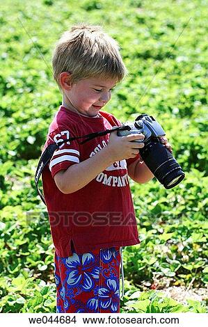 A five-year-old caucasian child views a photograph on the LCD screen of a digital camera. View Large Photo Image Picture - A five-year-old caucasian child views a photograph on the LCD screen of a digital camera.. Fotosearch