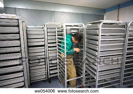 Middle-age man surrounded by racks that are filled with metal trays View Large Photo Image Stock Photograph - Middle-age man surrounded by racks that are filled with metal trays. Fotosearch