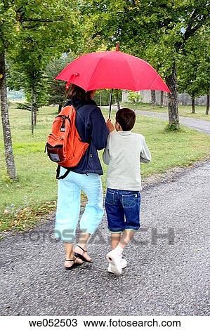 Mother and son strolling in the rain. View Large Photo Image Stock Image - Mother and son strolling in the rain.. Fotosearch