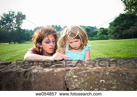 Mother showing her young daughter something on a rock wall View Large Photo Image Stock Photo - Mother showing her young daughter something on a rock wall. Fotosearch