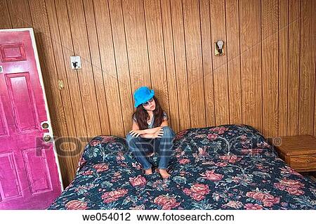 Preteen girl, wearing sunglasses and a funny blue hat, sitting on a bed in a motel room View Large Photo Image Stock Image - Preteen girl, wearing sunglasses and a funny blue hat, sitting on a bed in a motel room. Fotosearch