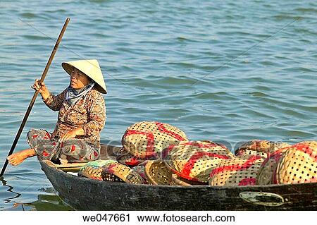 Stock Image - Woman in boat near fish market in Hoi An, Vietnam.. Fotosearch