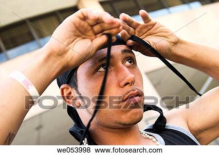 Young Hispanic man putting on a cloth cap View Large Photo Image Stock Photo - Young Hispanic man putting on a cloth cap. Fotosearch