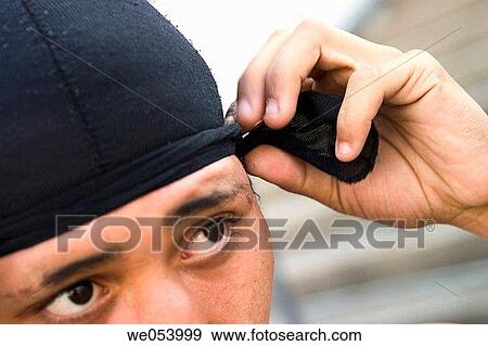Young Hispanic man putting on a cloth cap View Large Photo Image Stock Photo - Young Hispanic man putting on a cloth cap. Fotosearch