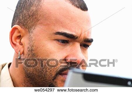Stock Photo - Young man working outside on his laptop computer. Fotosearch