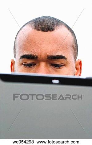 Stock Photo - Young man working outside on his laptop computer. Fotosearch