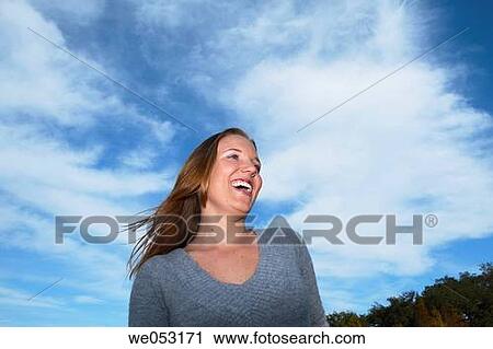 Young woman laughing off camera with the blue sky in the background. View Large Photo Image Stock Image - Young woman laughing off camera with the blue sky in the background.. Fotosearch
