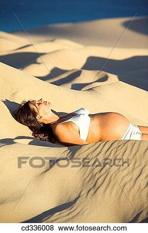 Stock Photo - Pregnant Woman Lying on a Dune. Fotosearch