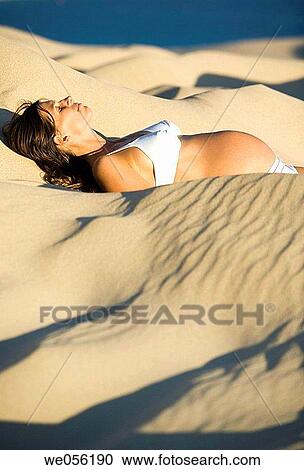 Stock Image - Pregnant Woman Lying on a Sand Dune. Fotosearch