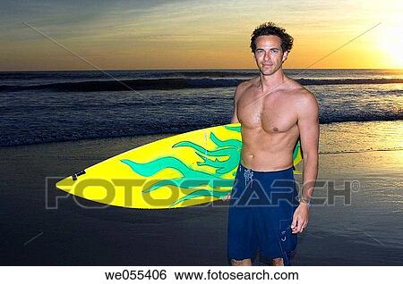 surfer on the beach with sunset in the background View Large Photo Image Stock Photograph - surfer on the beach with sunset in the background. Fotosearch