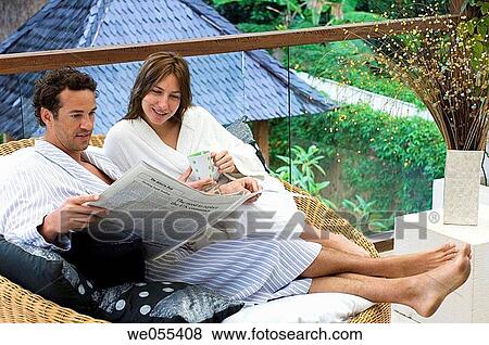 young couple in bathrobe sitting and reading newspaper on sofa View Large Photo Image Stock Photo - young couple in bathrobe sitting and reading newspaper on sofa. Fotosearch
