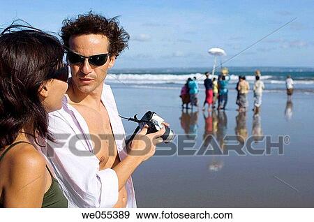 Stock Photo - young couple taking snapshot on the beach. Fotosearch