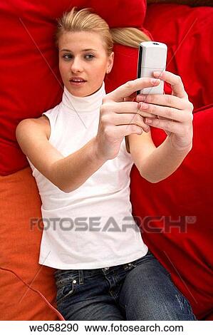 Stock Image - blond, camera, cell phone. Fotosearch