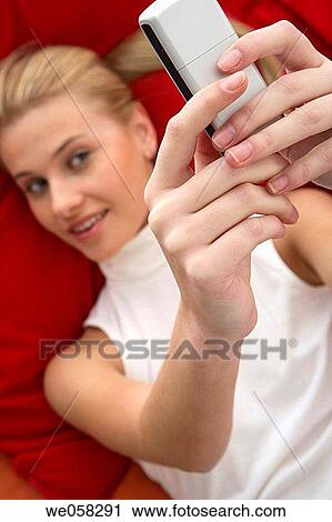 Stock Image - blond, camera, cell phone. Fotosearch