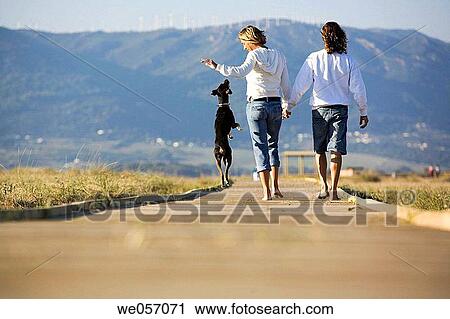 Stock Image - Couple Playing With Their Dog. Fotosearch