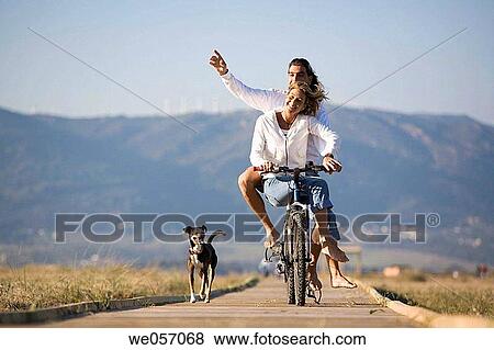 Couple Ridding a Bike With Their Dog View Large Photo Image Stock Photo - Couple Ridding a Bike With Their Dog. Fotosearch